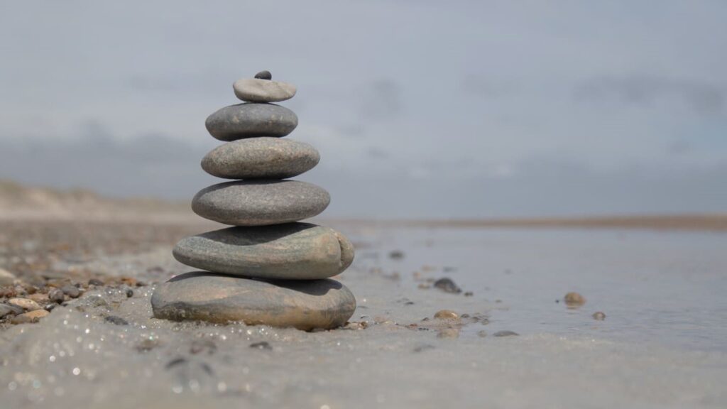 Gestapelde stenen aan zee als symbool voor innerlijke rust en balans trainen