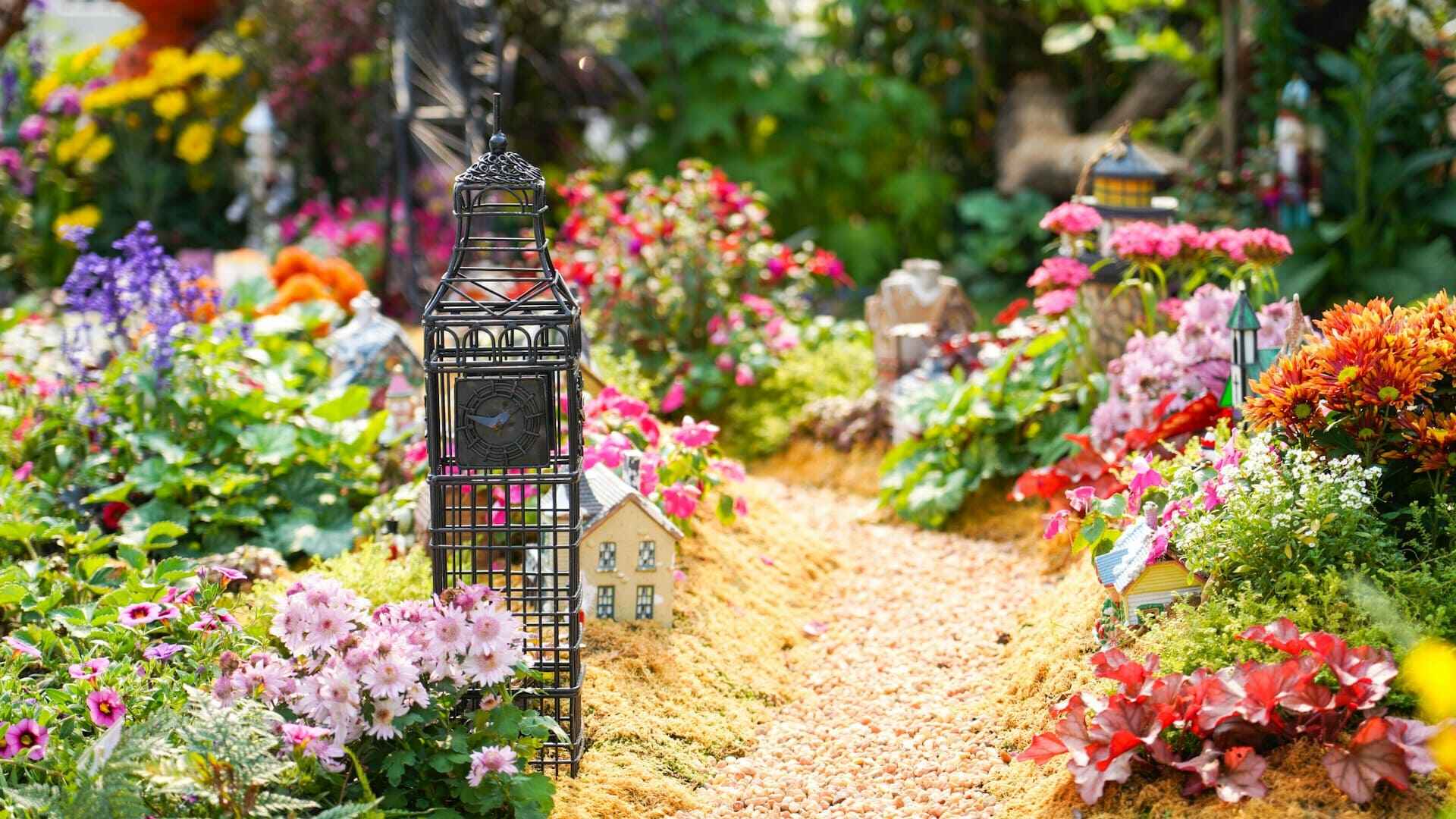 Kleurrijke tuin vol bloemen, miniatuurhuisjes en decoratieve elementen – creatieve inspiratie voor tuin upgraden met kleur.