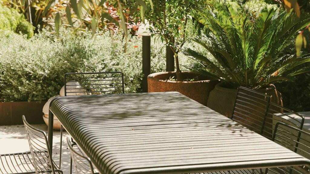 Moderne tuintafel met metalen stoelen omringd door weelderig groen, perfect voor tuin upgraden met eigentijdse meubels.