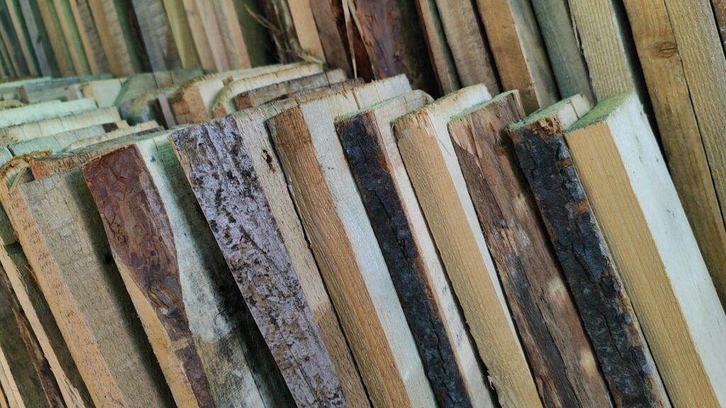 Ongeschuurde planken met schors laten zien waarom hout beschermen buiten essentieel is tegen vocht en slijtage.
