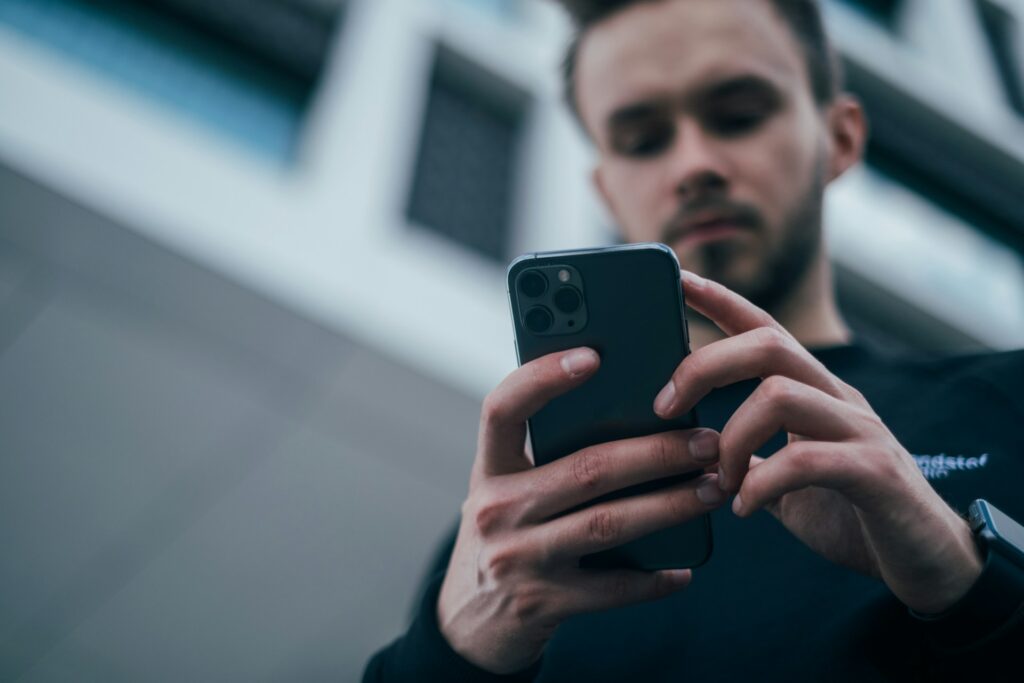 Persoon gebruikt smartphone buiten terwijl telefoon schoonmaken helpt tegen vet en stof op het scherm.