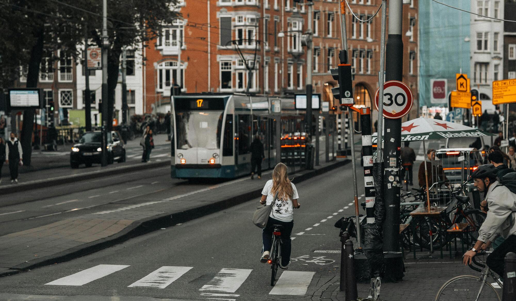 Fietser rijdt door drukke straat in stad met tram en geparkeerde fietsen