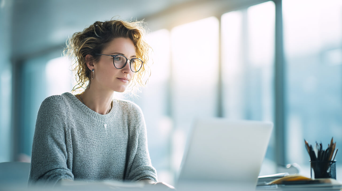 Professional werkt geconcentreerd achter laptop in een lichte kantoorruimte met een werkplek overzichtelijker ingericht